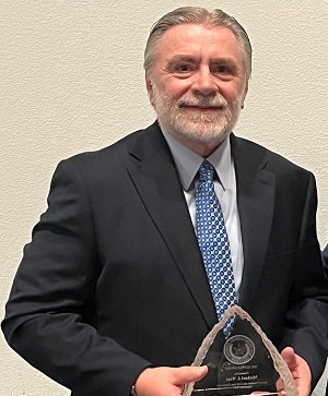 Assistant District Attorney Mike West holds an award.